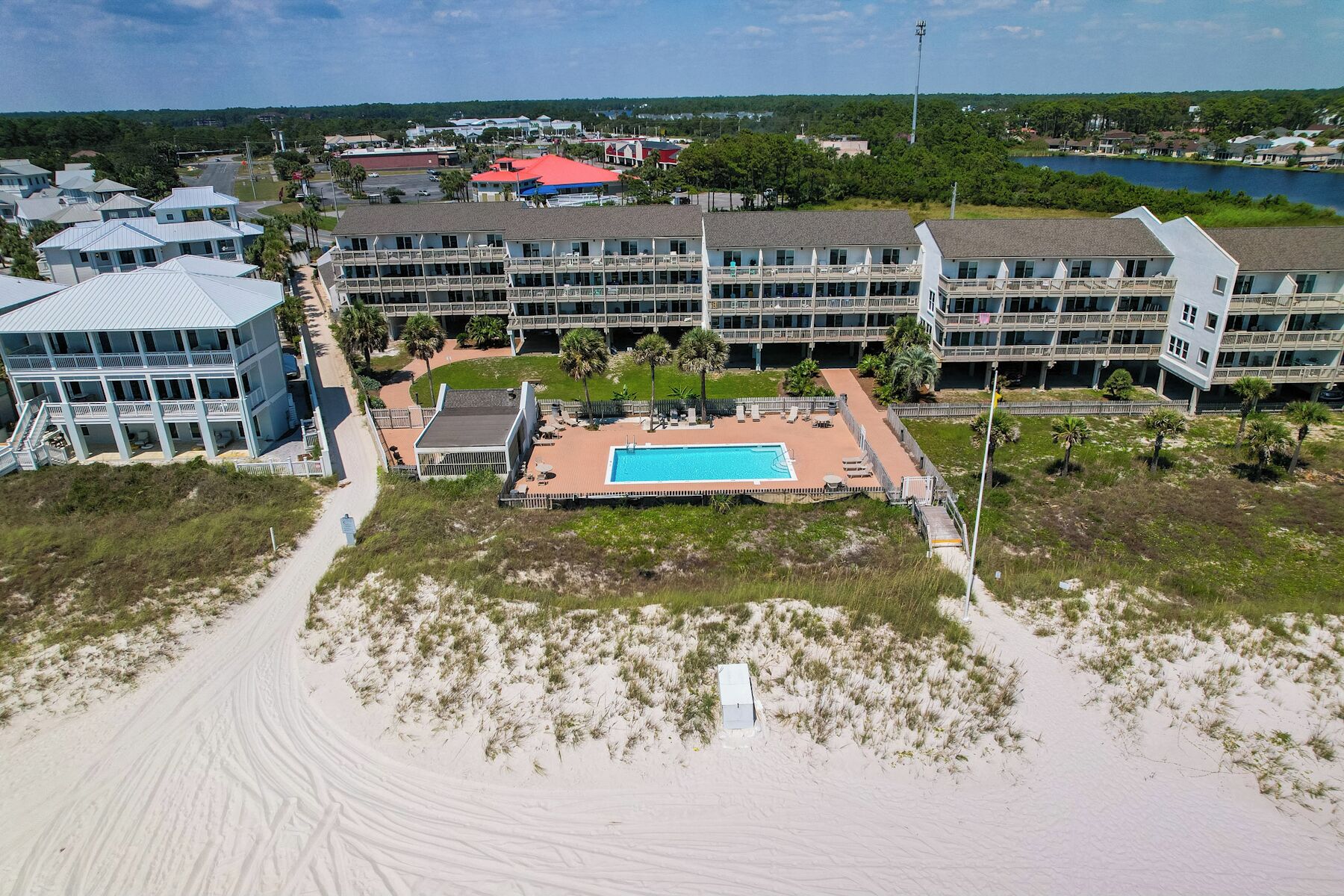 Un hotel frente a la playa con piscina, varios balcones y vistas panorámicas del entorno.