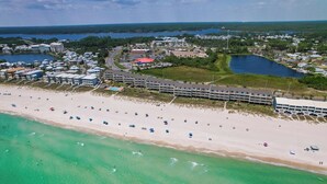 An aerial view of a coastal area with a sandy beach, a marina, and several buildings including a hotel with multiple floors and a parking lot. - Ramsgate 22 | Renovated Gulf-Front Escape (Panama City Beach)