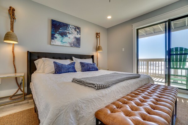 Une chambre avec un grand lit, un banc, un tableau et une vue sur l’extérieur.