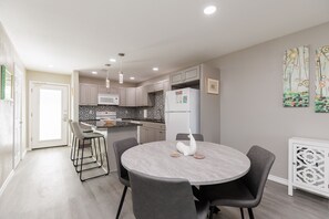 Une cuisine moderne avec un coin repas, comprenant une table ronde, des chaises et un réfrigérateur.