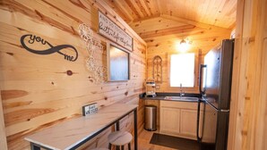 Ein gemütliches Holzhaus-Interieur mit einer Küche, die einen Edelstahl-Kühlschrank, eine Spüle und eine Weinkühllanze enthält.