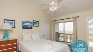 A clean, well-lit bedroom with a bed, a dresser, a ceiling fan, and a balcony with a view. - Beachside Paradise | Beach Views, Pool & Hot Tub (Corpus Christi)