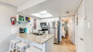 A modern kitchen with a central island, white cabinetry, stainless steel appliances, and a skylight. - Beachside Retreat | Pool, Hot Tub & Beach Access (Corpus Christi)