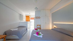 Quarto de hotel com duas camas, uma mesa de madeira, uma cadeira e um guarda-roupa.