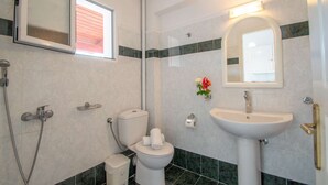 Casa de banho com sanita, bidé, lavatório e espelho.