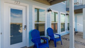 A house with the number 122, two blue Adirondack chairs, and a gravel driveway. - Pet-Friendly Coastal Retreat | Pool, Hot Tub & King Bed (Corpus Christi)