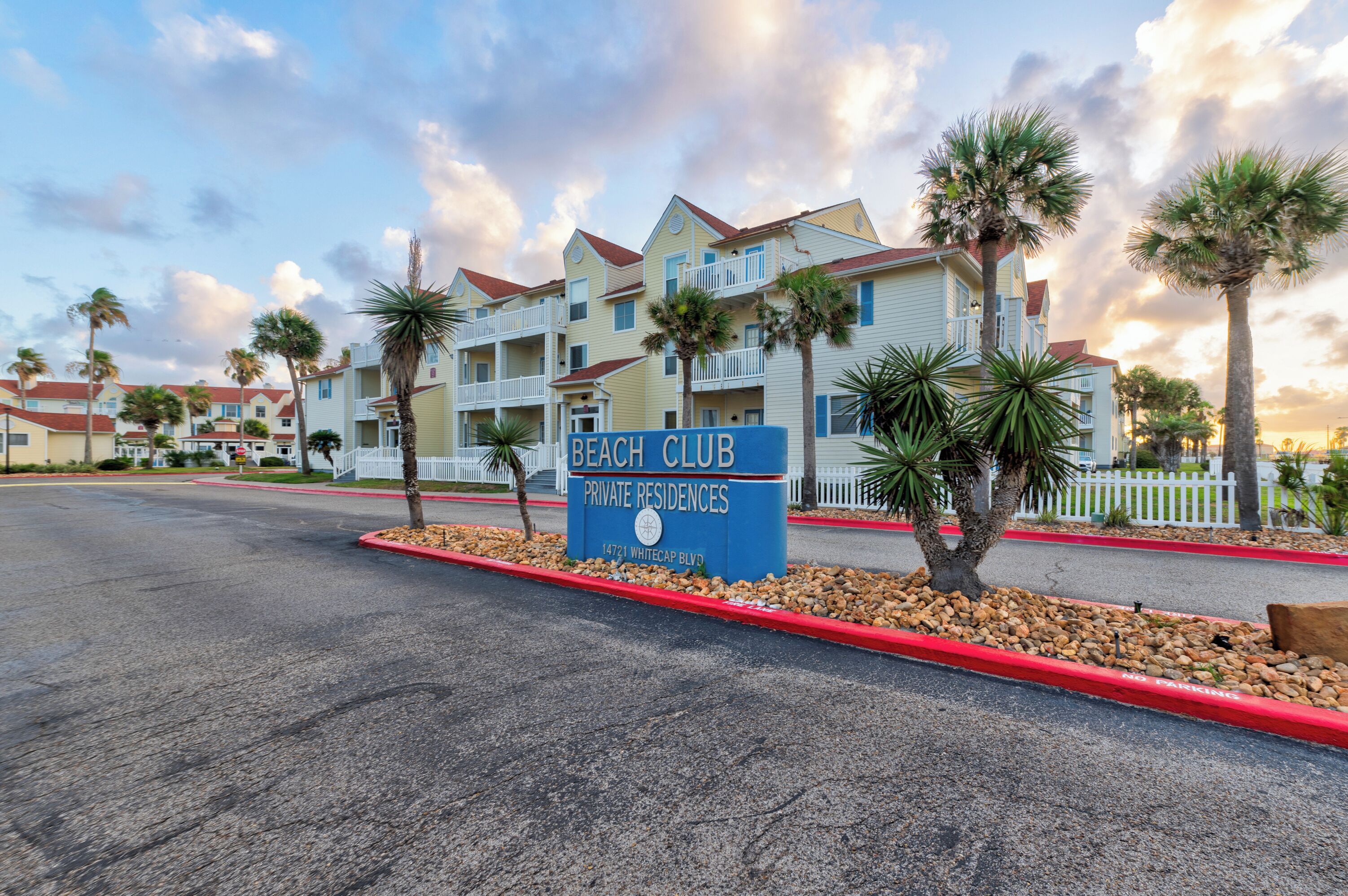 A beachfront hotel with a sign reading "Beach Club Private Residences" at 14721 Whitecap Blvd.