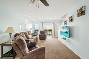 A living room with a sofa, armchair, and a television on a wall. - Spacious Beachside Escape | 3 Balconies, Gulf Views & Heated Pool (Corpus Christi)