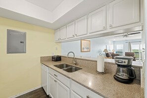A kitchen with a double sink, a toaster, a coffee maker, and a framed picture on the wall.