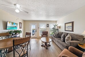 Ein Wohnzimmer mit Esstisch, Stühlen, einer Couch, einem Deckenventilator und einem Fernseher.