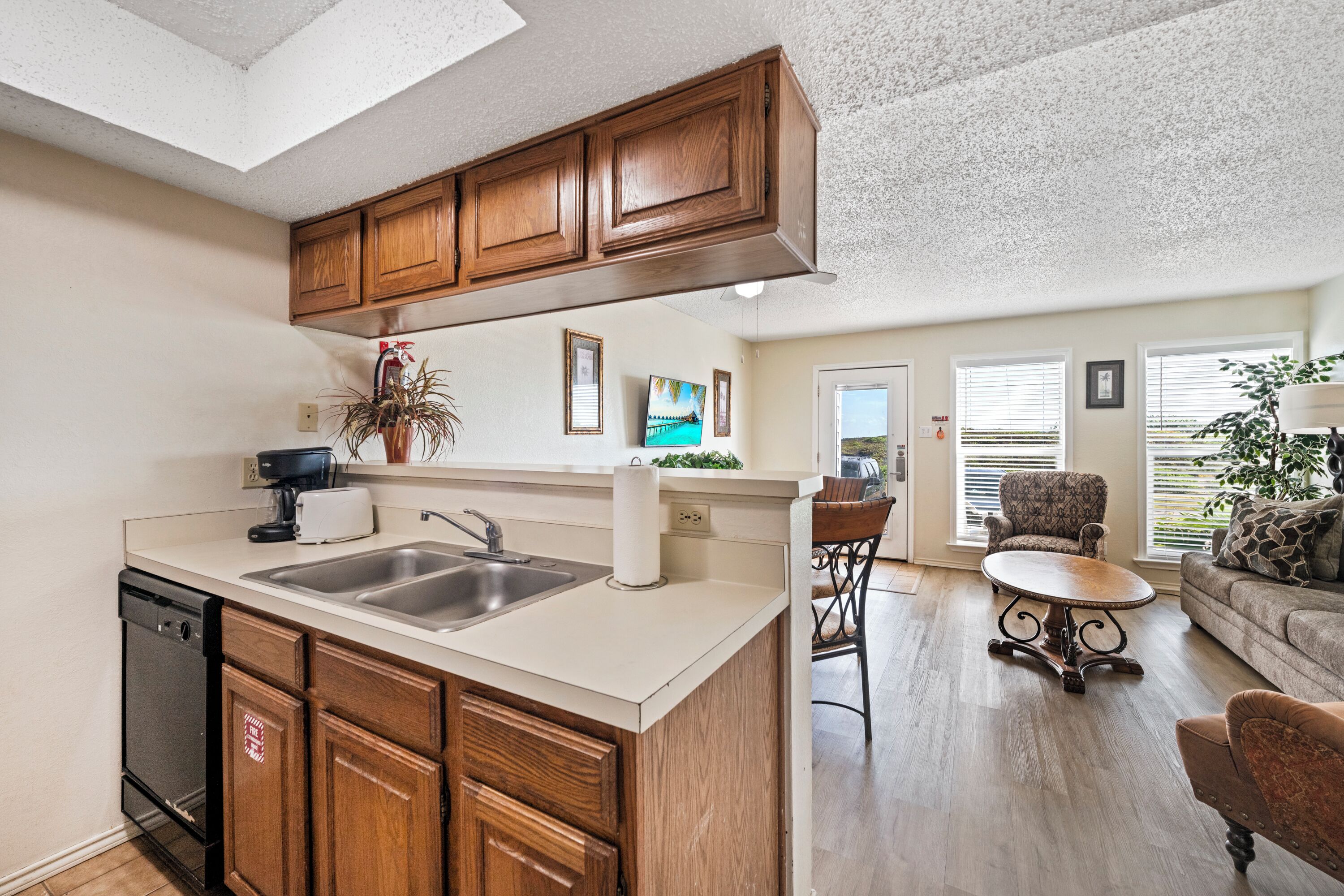 A kitchen with a central island, wooden cabinets, a dishwasher, and a coffee maker.