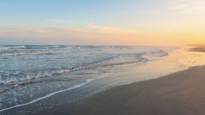 A beach with waves gently lapping onto the shore. - Beachfront Escape | Heated Pool & Gulf Views (Corpus Christi)