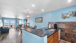 A modern kitchen with a dark countertop, wooden cabinets, and a view to the outside. - Beachfront Escape | Heated Pool & Gulf Views (Corpus Christi)