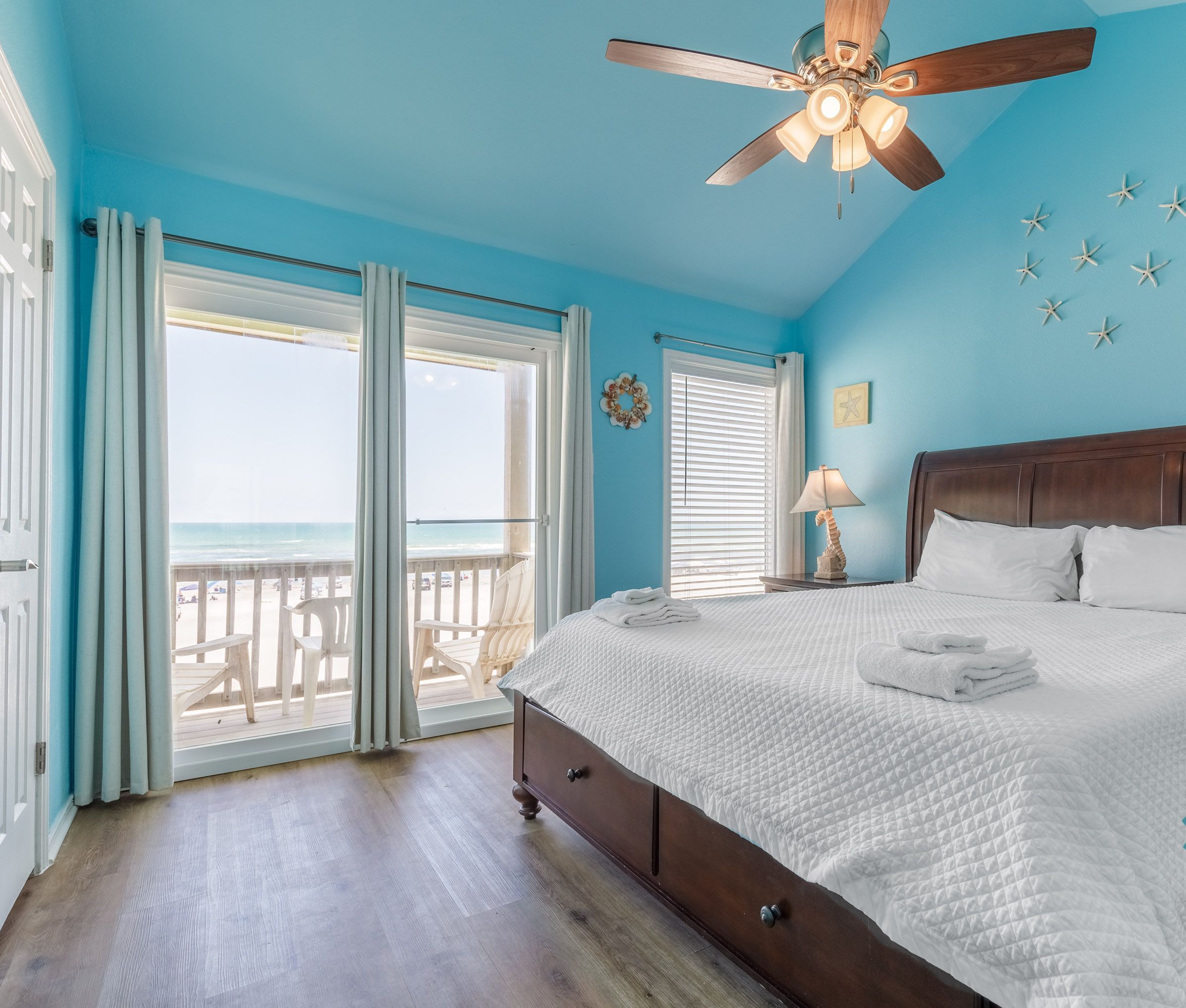 Ein Schlafzimmer mit Bett, Deckenventilator und Blick auf den Strand, sowie einem ‚Clean Bed Promise‘-Abzeichen.