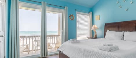 Ein Schlafzimmer mit Bett, Deckenventilator und Blick auf den Strand, sowie einem ‚Clean Bed Promise‘-Abzeichen.