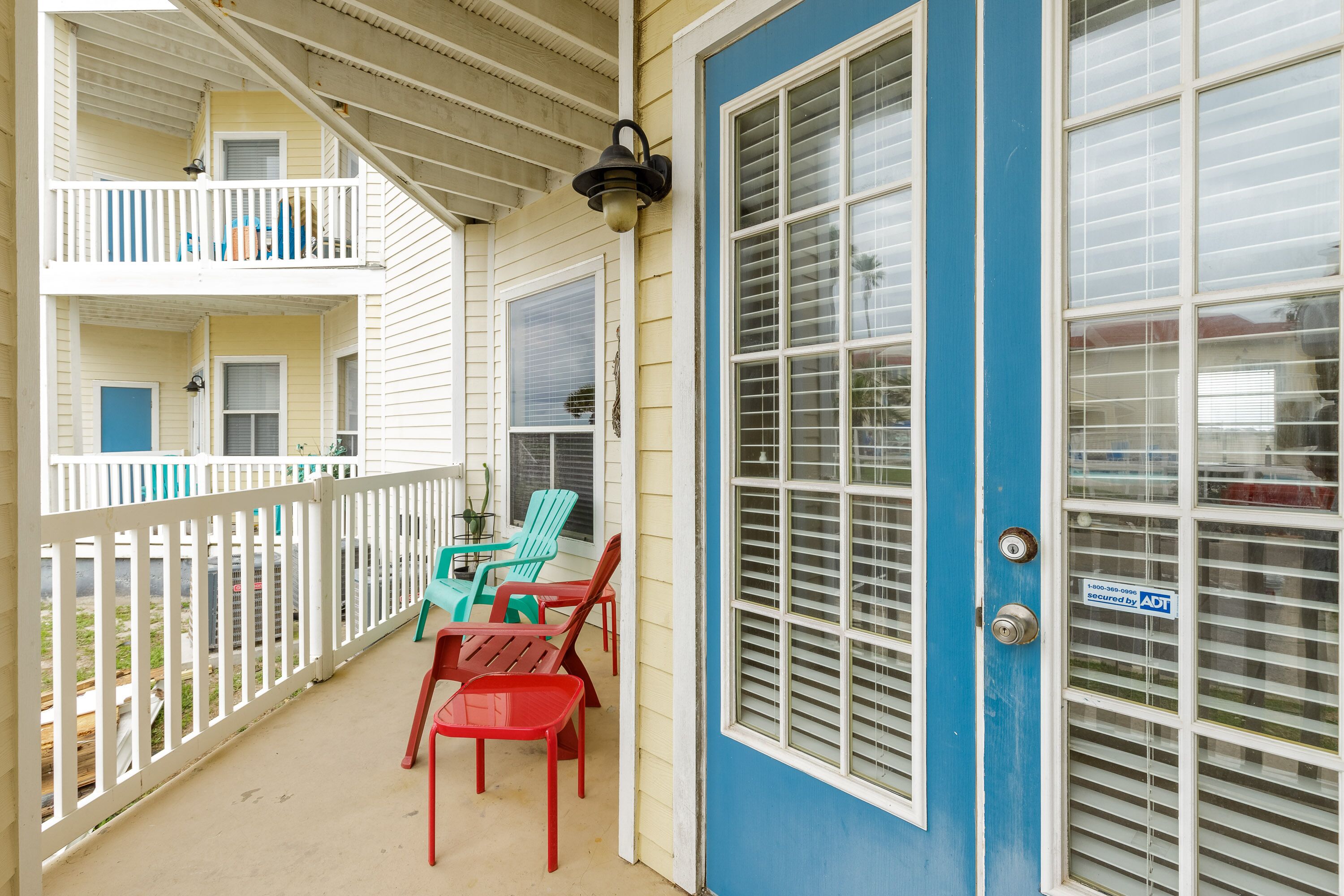 A balcony with red chairs and a blue door.