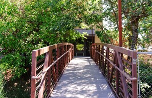 Un pont piétonnier doté de garde-corps en métal, entouré d’une végétation luxuriante.