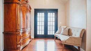 A room with a wooden wardrobe, a beige sofa, and a dark double door with windows. - 6 bedroom Large house in Pickwick district Springfield Near MSU (Springfield)