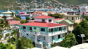 A coastal town with colorful buildings, a marina with boats, and a mountainous backdrop.