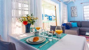 A breakfast table with a croissant, orange juice, and water glasses, set against a bright window with a view of buildings.