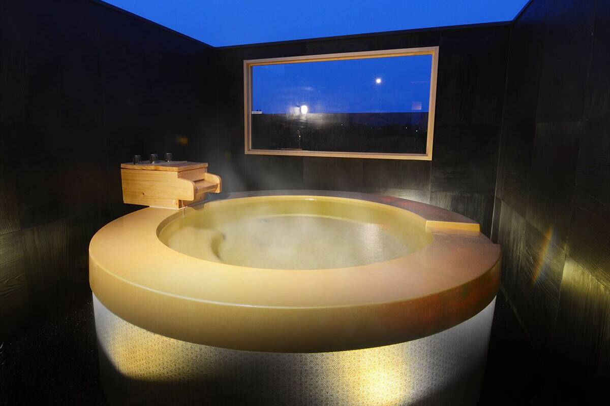 Ein Whirlpool mit einer Holzbank, einem Holzregal und einem Rahmen, der den Nachthimmel zeigt.