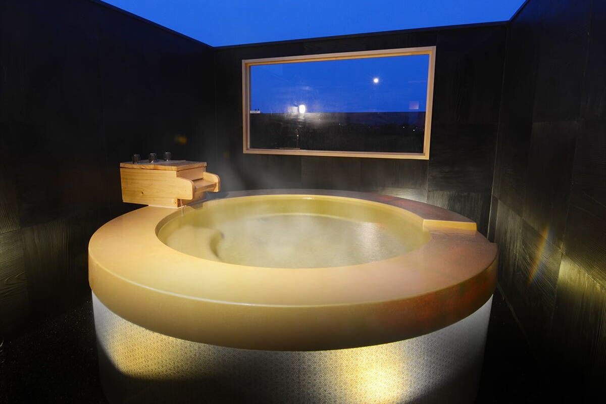Un jacuzzi con un banco de madera, un estante de madera y una vista enmarcada del cielo nocturno.
