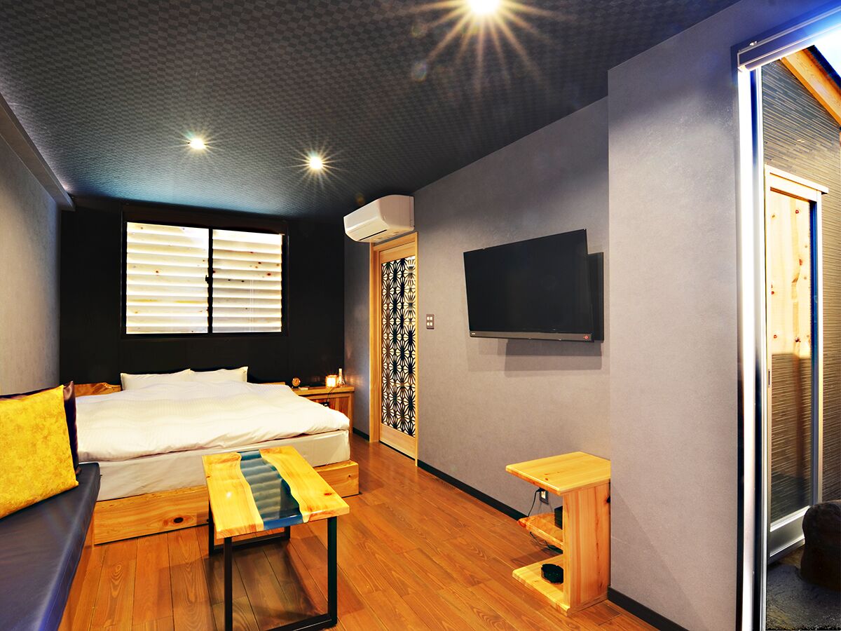 A room with a bed, a small table, a TV, and a sliding door.
