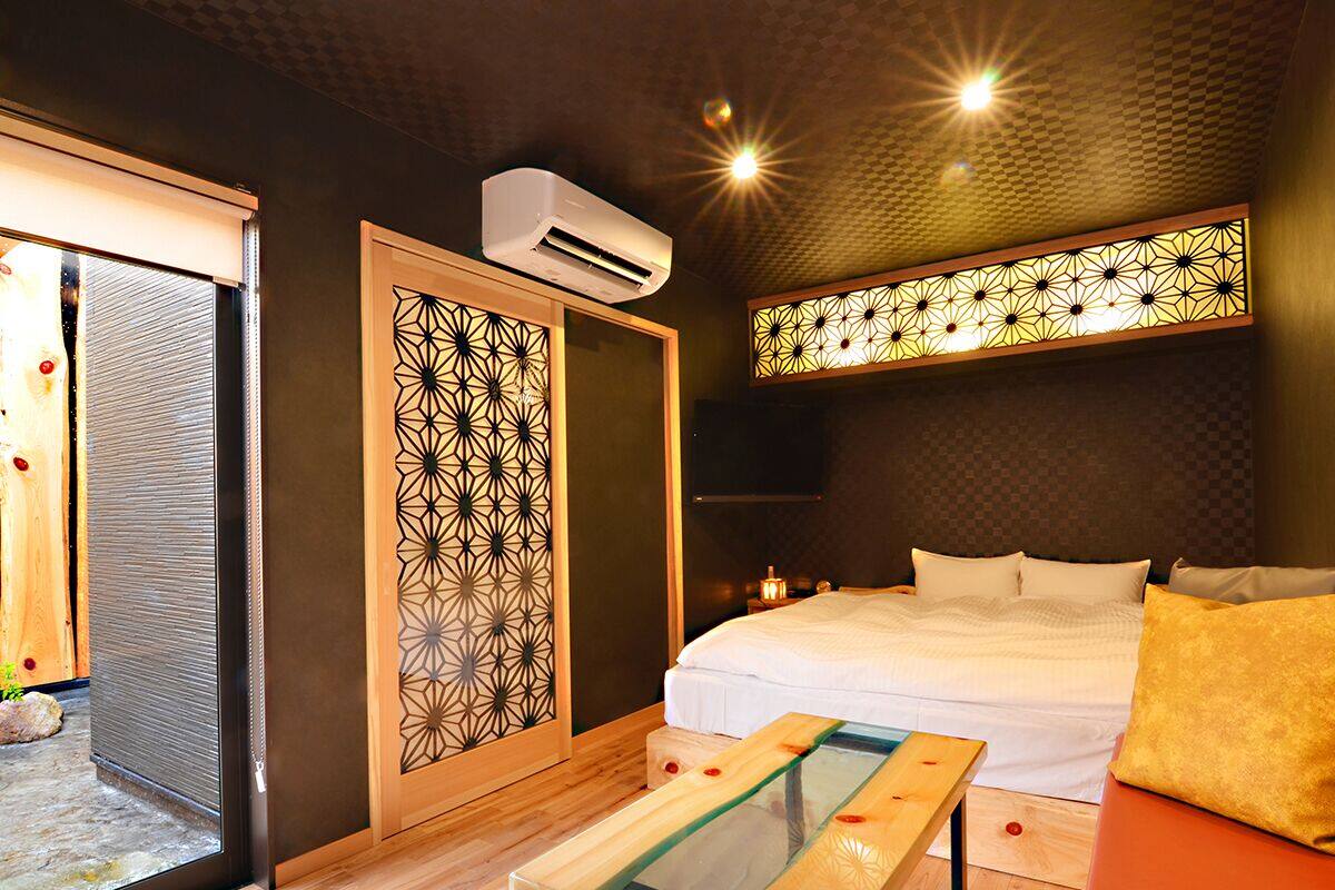 Ein modernes Hotelzimmer mit einem Bett, einem Glastisch, einem Dekorationselement und einer Klimaanlage.
