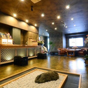 A reception area with a counter, seating, and a decorative rock centerpiece. - Nihon Ryokan Utsuwa Beppu Kannawa (Beppu)