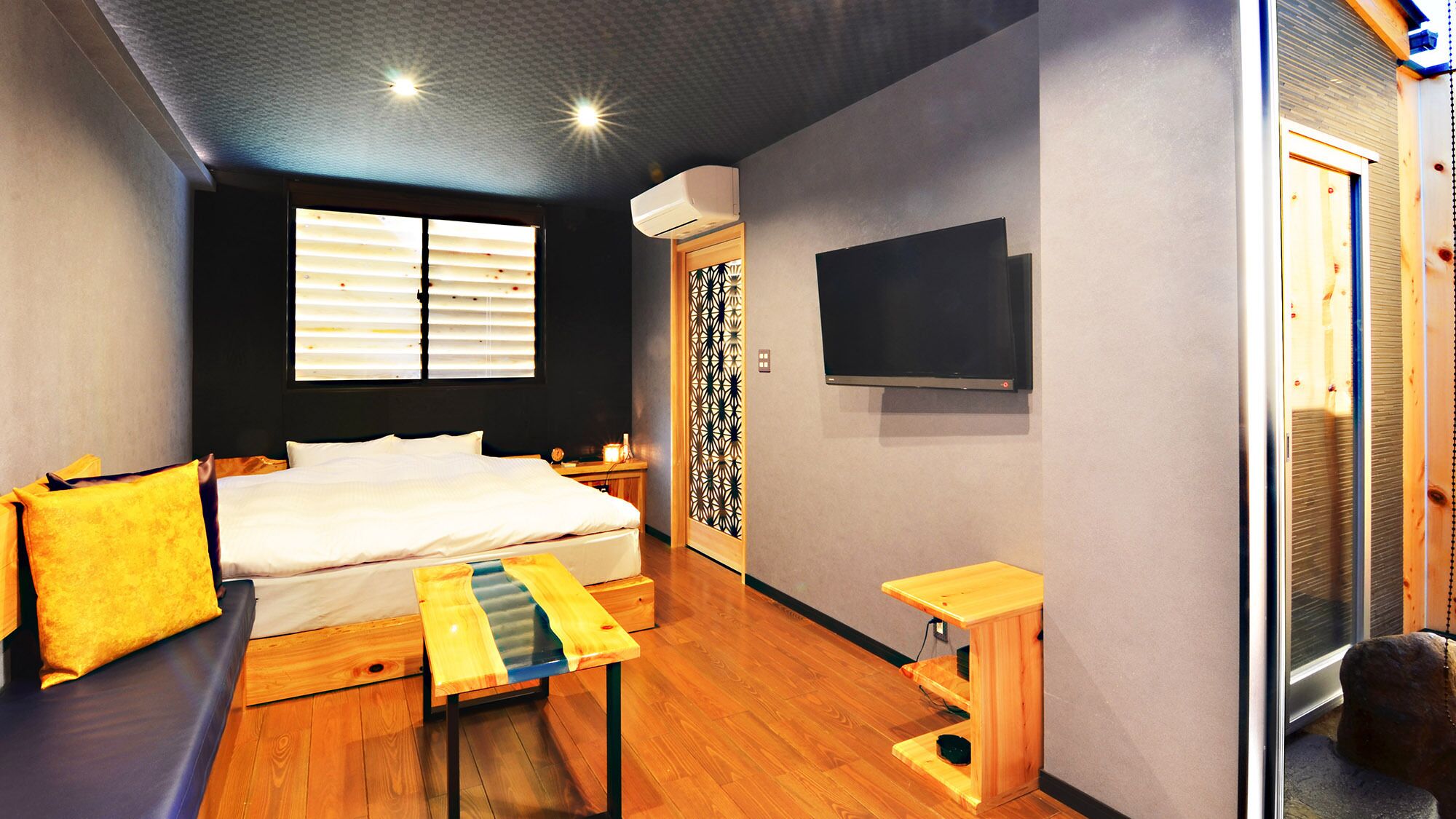 A modern bedroom with a bed, bedside table, and a TV mounted on the wall.