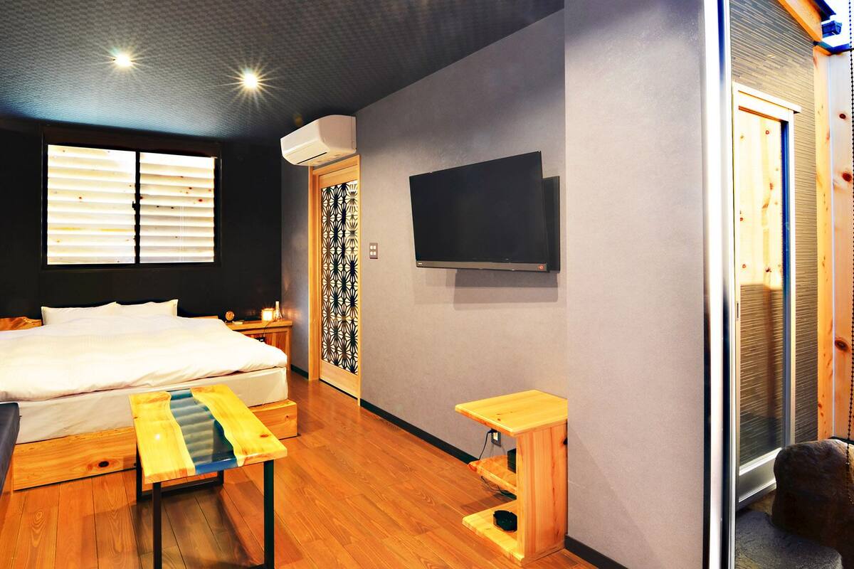 Ein modernes Schlafzimmer mit Bett, Nachttisch und einem an der Wand befestigten Fernseher.