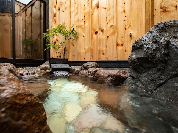 Un mur en bois, une petite cascade et une formation rocheuse.