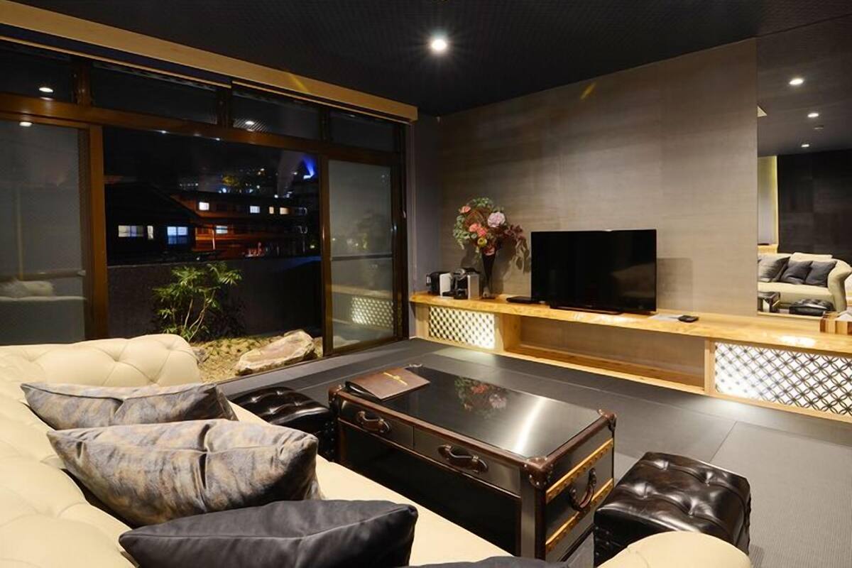 Ein modernes Wohnzimmer mit einer Couch, einem Couchtisch, einem Fernseher und einer dekorativen Vase.