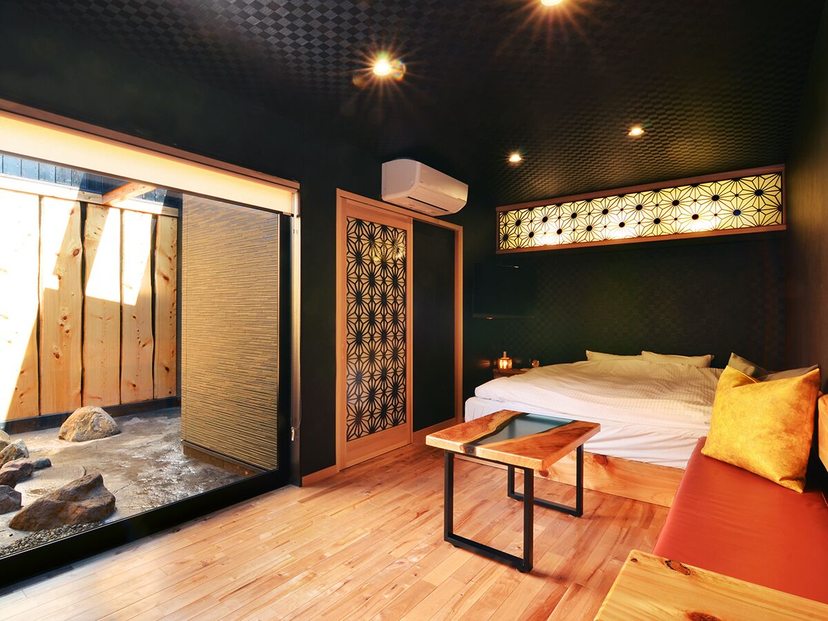 A room with a bed, a wooden table, a decorative screen, and a small water feature.
