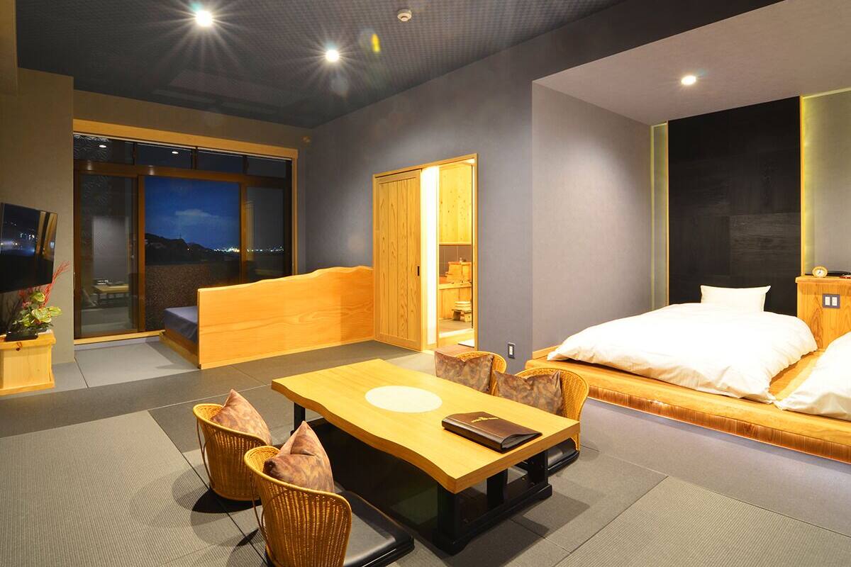 Ein modernes Hotelzimmer mit einer Couch, einem Holztisch, einem Fernseher und einem großen Fenster.