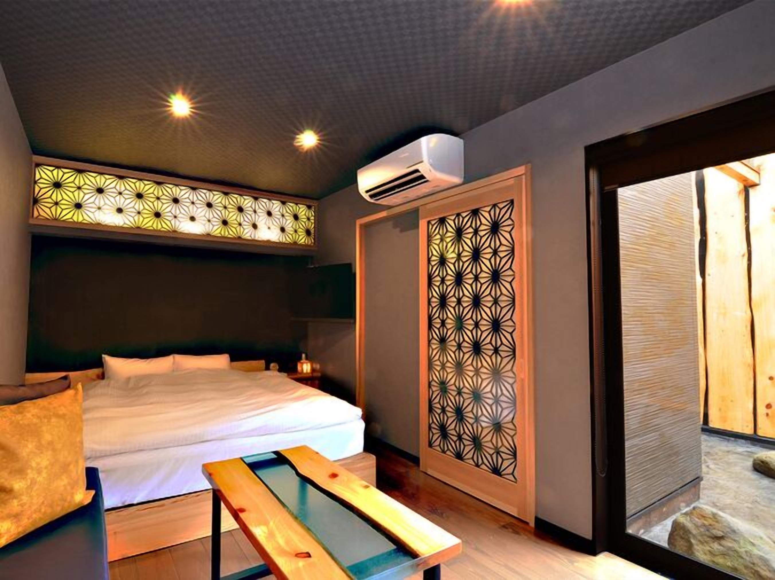 Une chambre moderne comprenant un lit, une table de chevet, des panneaux muraux décoratifs et un appareil de climatisation.