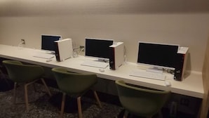 A row of computer workstations with chairs, each with a keyboard and monitor. - Good Bless Garden Sauna Stay (Yonago)