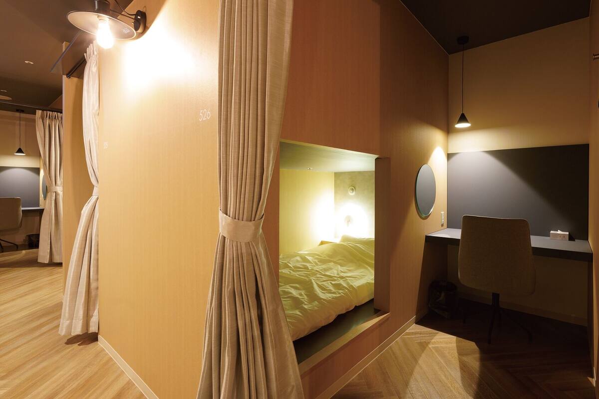 Une chambre d’hôtel avec un lit, un bureau, une chaise et un rideau.
