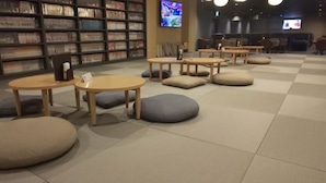 A library with bookshelves, tables, and chairs. - Good Bless Garden Sauna Stay (Yonago)