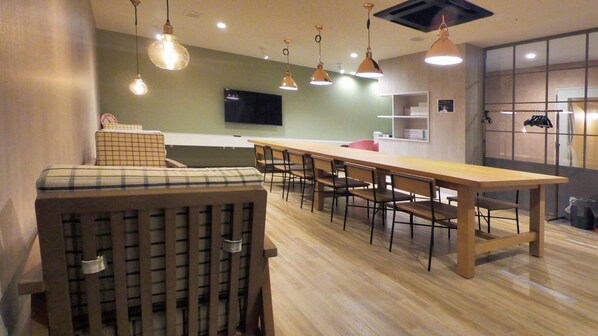 A modern kitchen with wooden countertops, a long dining table, and pendant lighting. - Good Bless Garden Sauna Stay (Yonago)