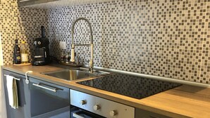 Una cocina moderna con salpicadero de azulejos blanco y negro, electrodomésticos de acero inoxidable y encimeras de madera.