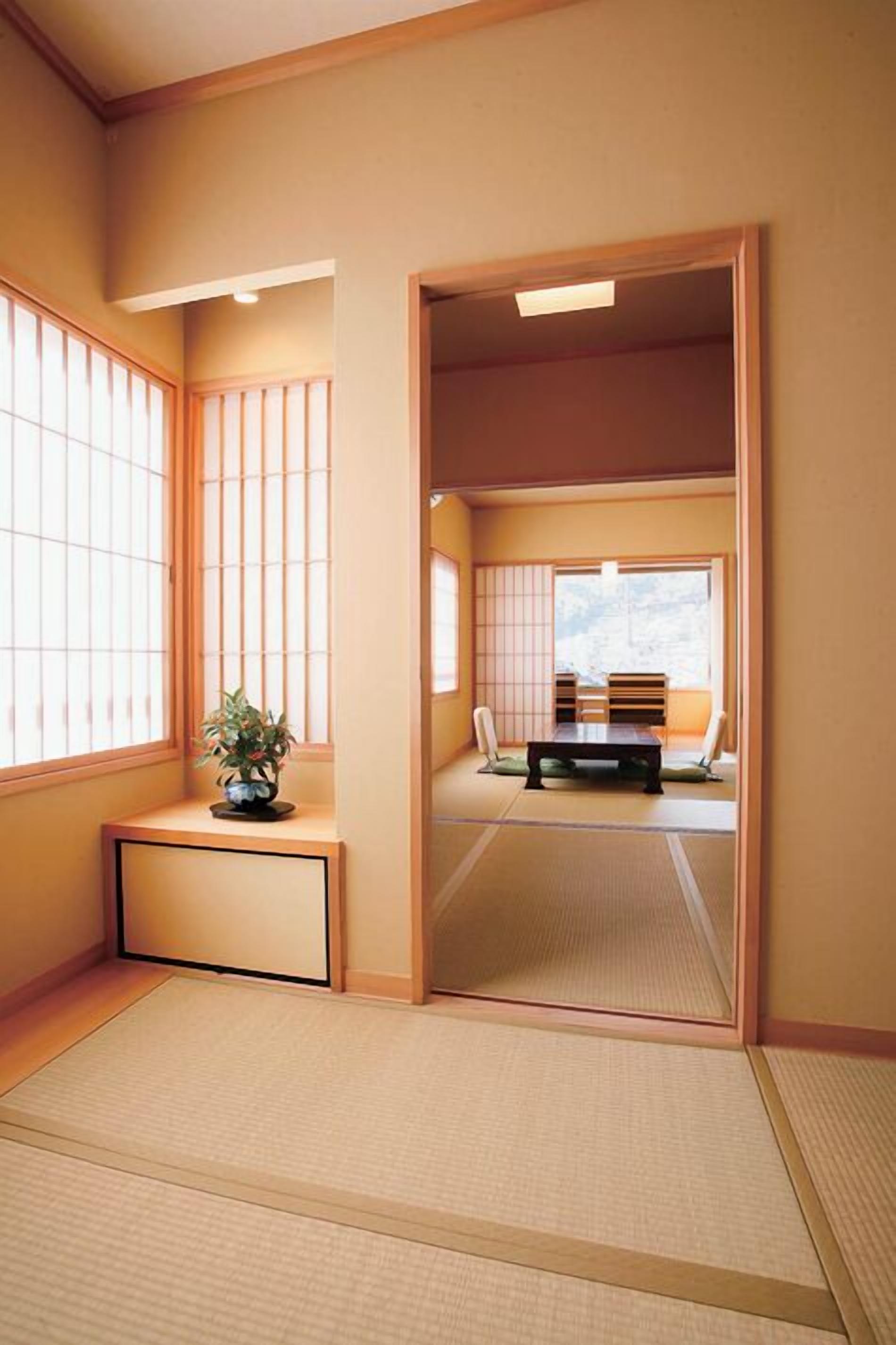 A traditional Japanese room with tatami flooring, sliding doors, and a low table with cushions.