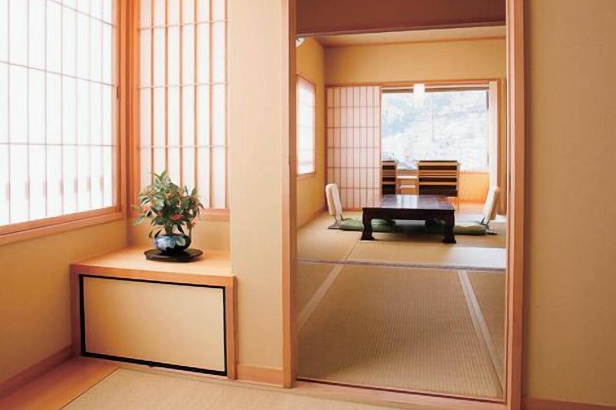 Een traditionele Japanse kamer met tatami vloerbedekking, schuifdeuren en een lage tafel met kussens.