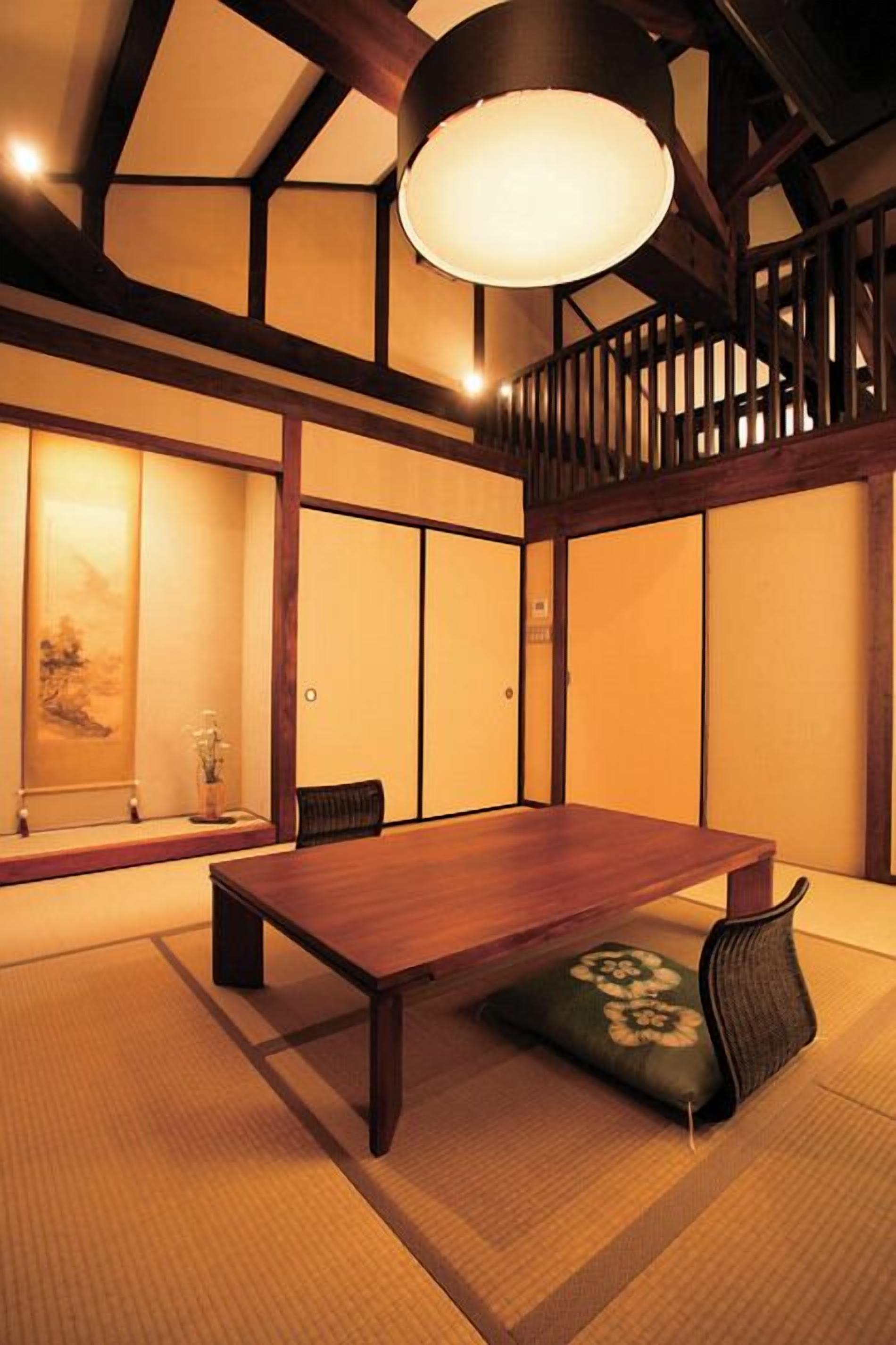 A traditional Japanese-style room with tatami flooring, a low wooden table, and a hanging light fixture.