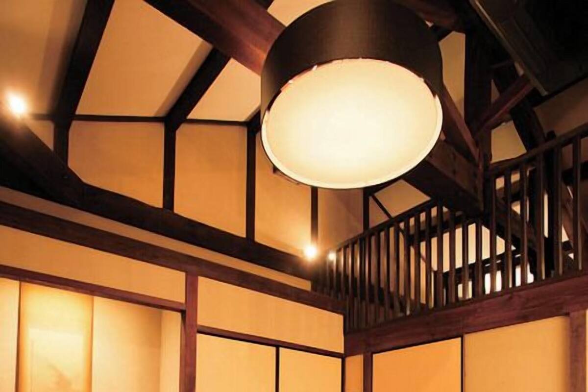 Een traditionele Japanse kamer met tatami vloerbedekking, een lage houten tafel en een hangende lamp.