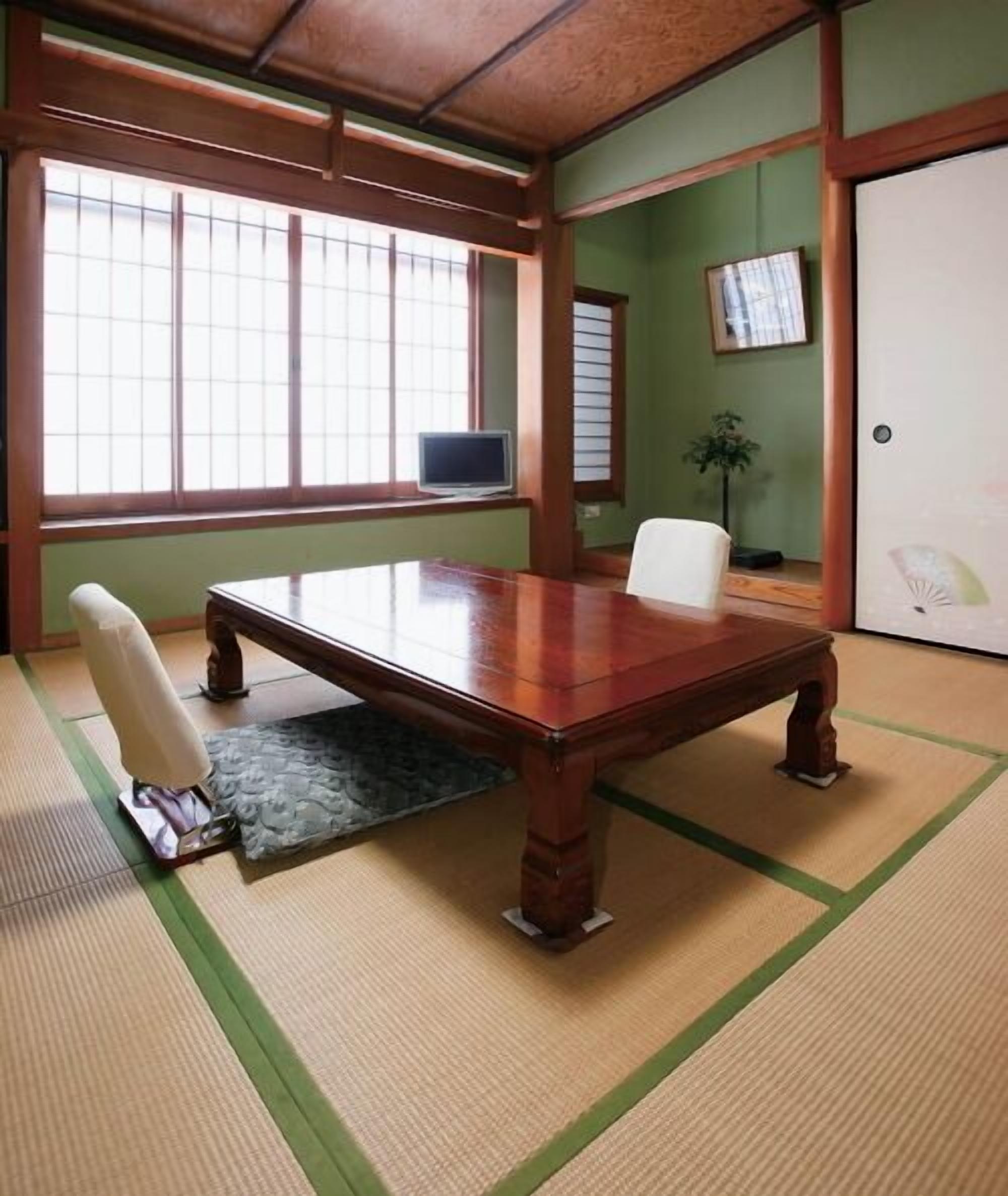 A traditional Japanese room with tatami flooring, a wooden table, and sliding doors.