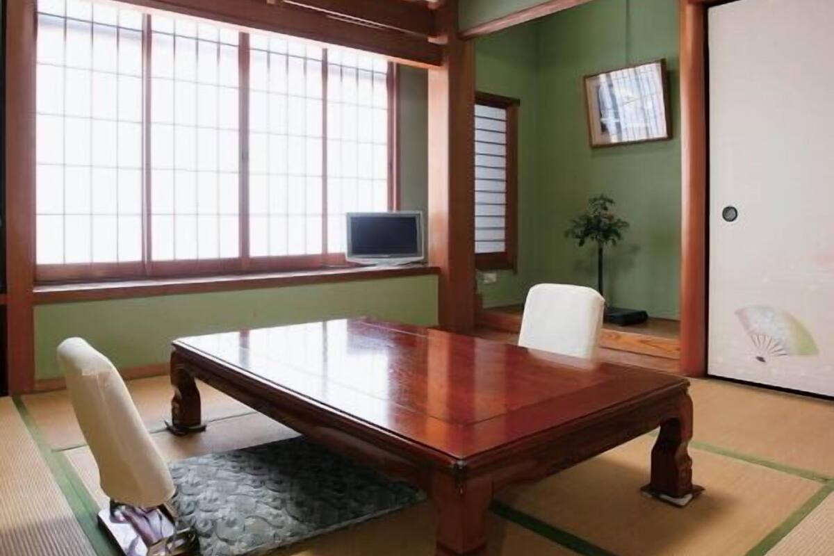 Een traditionele Japanse kamer met tatami vloerbedekking, een houten tafel en schuifdeuren.