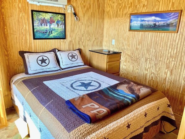 Un lit avec une couverture à motifs étoilés, une tête de lit en bois et une table de chevet avec une lampe.