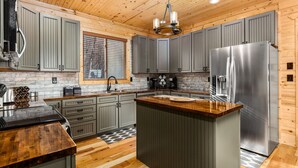 Una cocina moderna con techo de madera, gabinetes grises, electrodomésticos de acero inoxidable y una isla central.