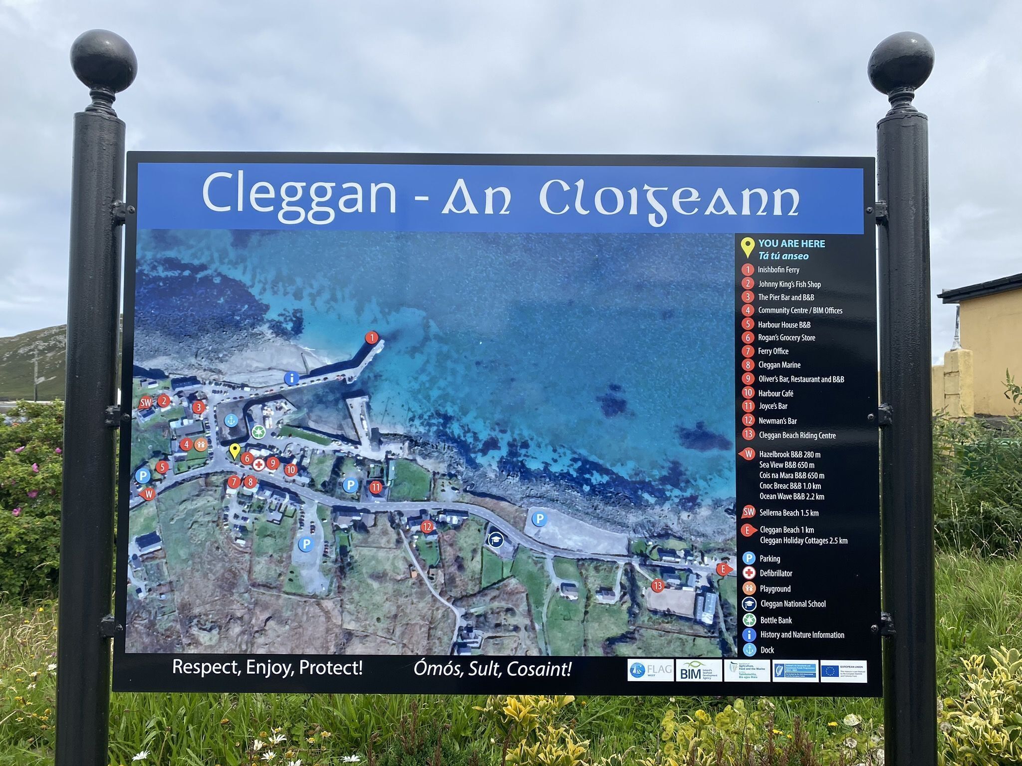 A sign with a map and a list of local attractions and amenities in Cleggan - An Cloiteann.